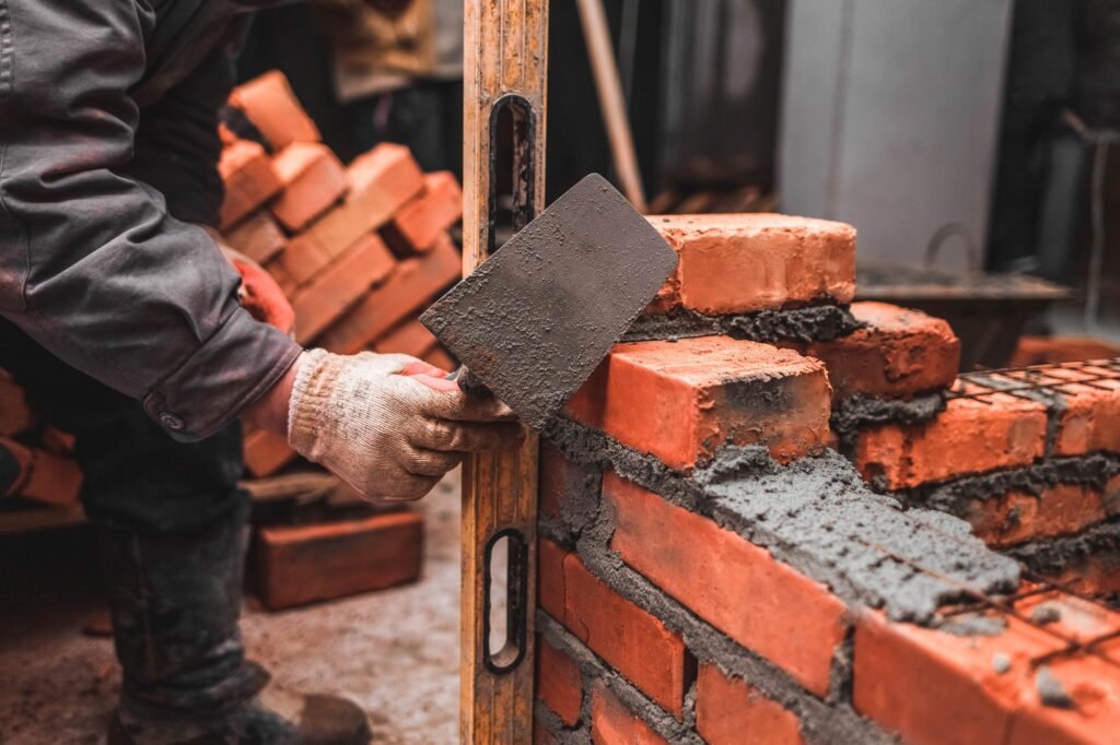 Bricklayer puts bricks to make a wall
